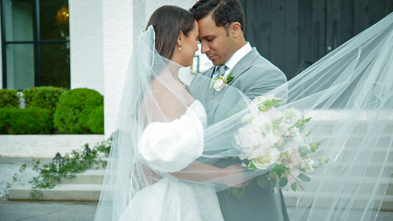Bride and groom embracing beneath a flowing veil