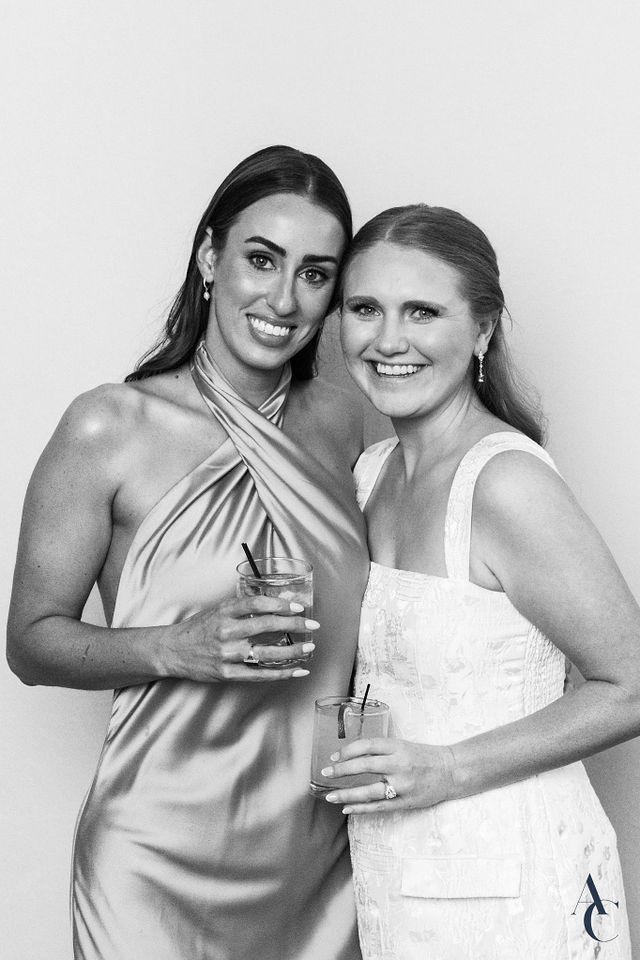 Bride and a guest with drinks in hand, smiling