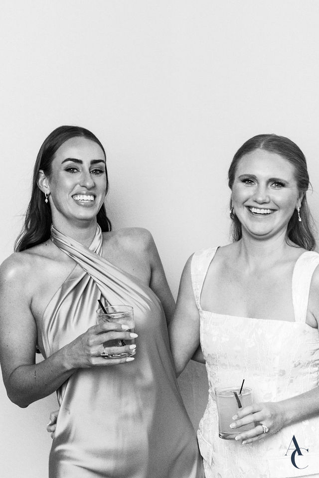 Two wedding guests toasting for the portrait station camera